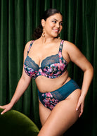 Woman wearing a floral lingerie set against a green curtain background