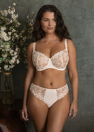 Woman wearing a white lace bra and panties set with a neutral background available at Leia Lingerie